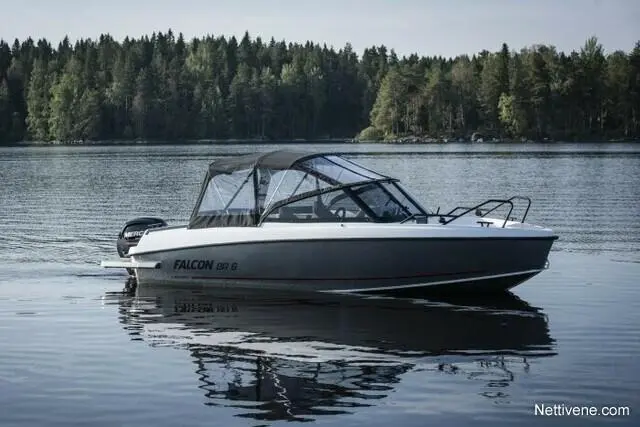 A Falcon BR 6 boat is cruising on a calm lake surrounded by lush green trees, reflecting on the water's surface.